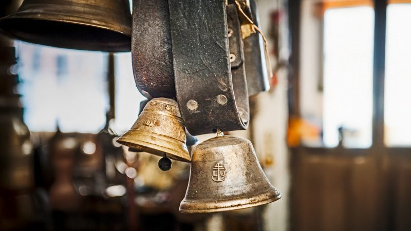 Nahaufnahme von handgeschmiedeten Kuhschellen in einem historischen Werkstatt-Umfeld.